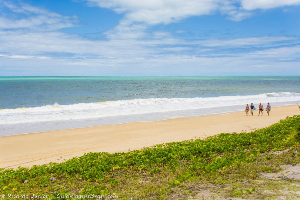 Imagem de casais caminhando pela Praia de Caraiva.
